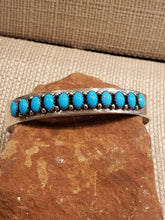 Load image into Gallery viewer, STUNNING VINTAGE! Features 11 Sleeping Beauty Turquoise Stones in this Sterling Silver Cuff Style Bracelet. 

Navajo HANDCRAFTED by Master Silversmith 

Paul Livingston circa 1980&#39;s

Approximately 10 mm wide. Opening 30 mm


