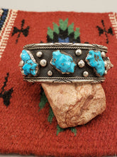 Load image into Gallery viewer, STUNNING NAVAJO HEAVY MEN&#39;S SIZE TURQUOISE BEAR CUFF BRACELET.

Metal - Sterling Silver 

Wrist Size -  fits a 7.75 inch wrist, and has a 1 9/16 inch gap

Width -  1.25 inches wide 

Overall Weight - 102 g  

Main Gemstone - 3 Carved KingmanTurquoise

NAVAJO HANDCRAFTED by artist from ALL TRIBES MANUFACTURERS 

FEATURES BEAR FACE ON EACH END


